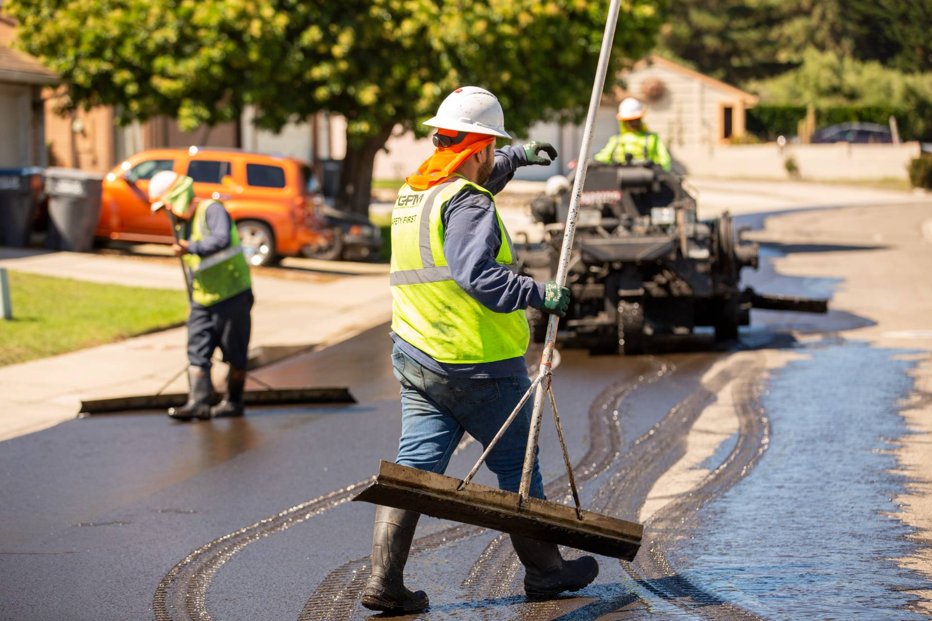 A GPM team member spreads the sealcoat that the buggy is laying down for Balboa Park.